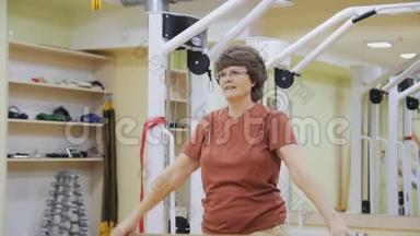 老年妇女伸展身体，在健身室用棍子做理疗。 健康体操。 积极主动